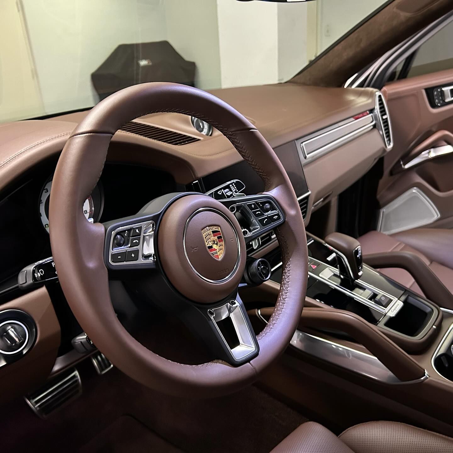 The inside of a porsche car with a brown steering wheel