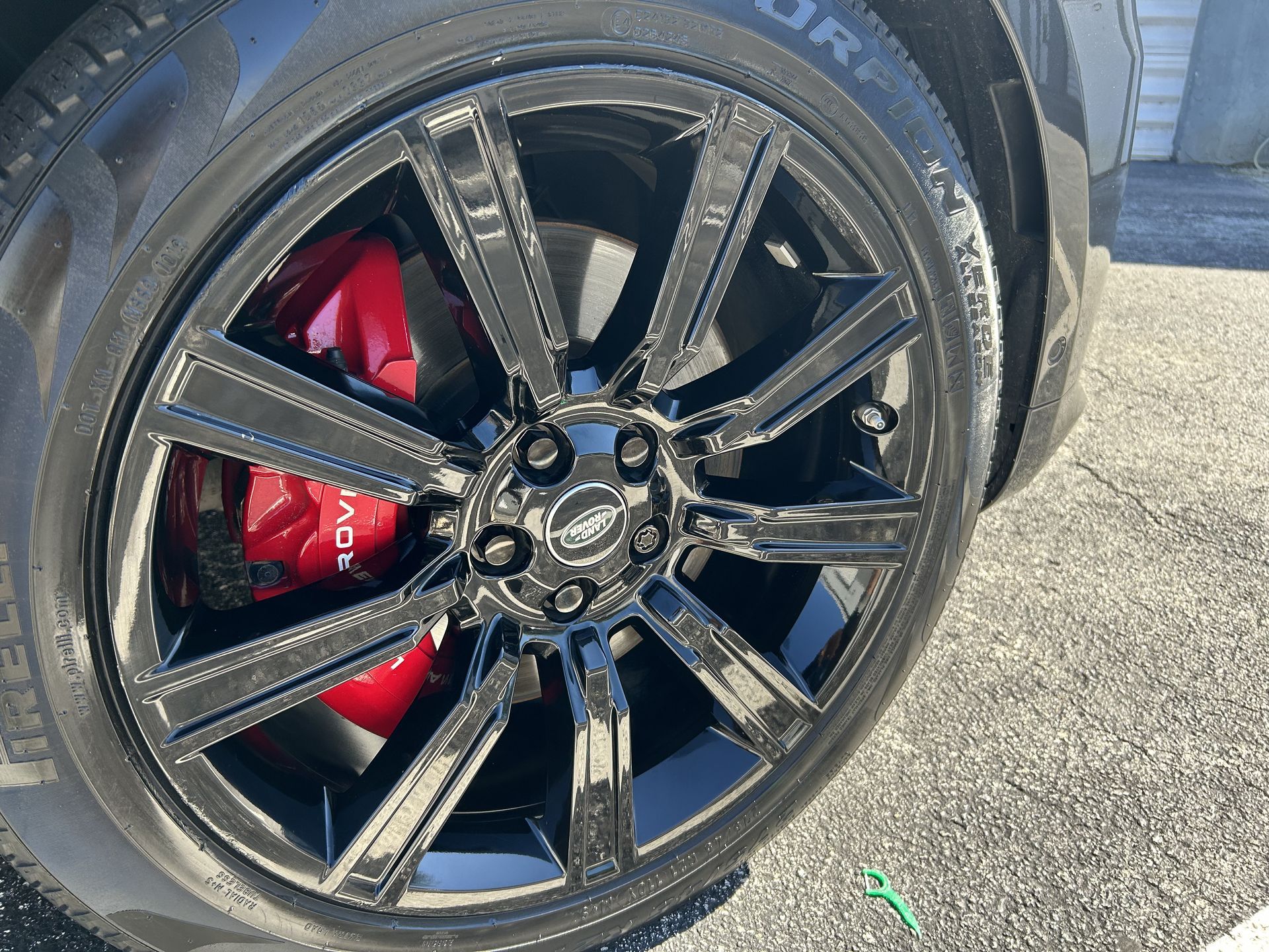 A close up of a black car wheel with red brake calipers.