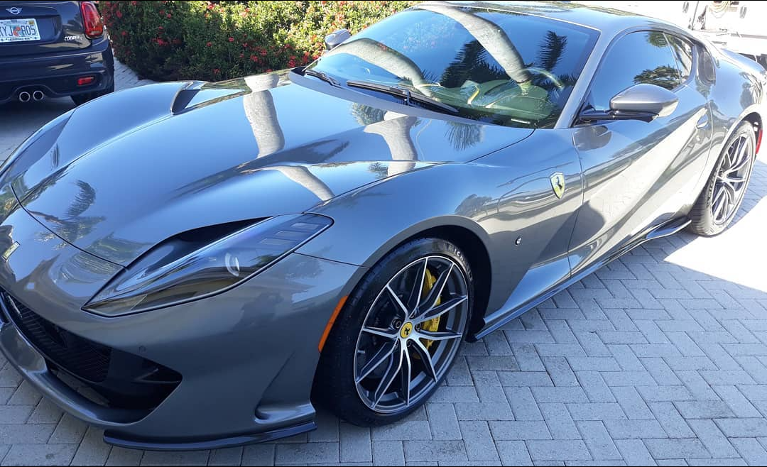 A gray ferrari is parked on a brick driveway.