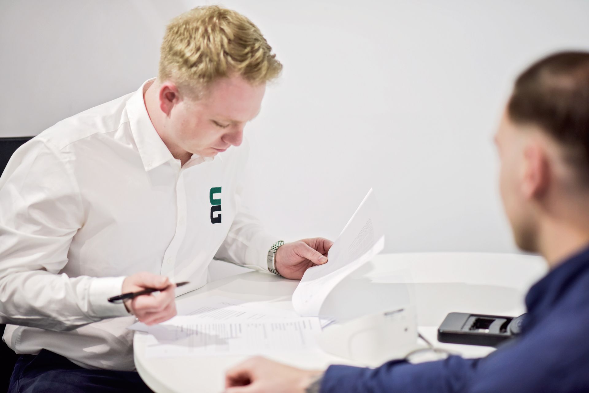 Two men are sitting at a table looking at a piece of paper.