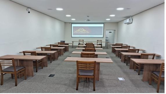 Uma sala grande com mesas e cadeiras e uma tela de projetor