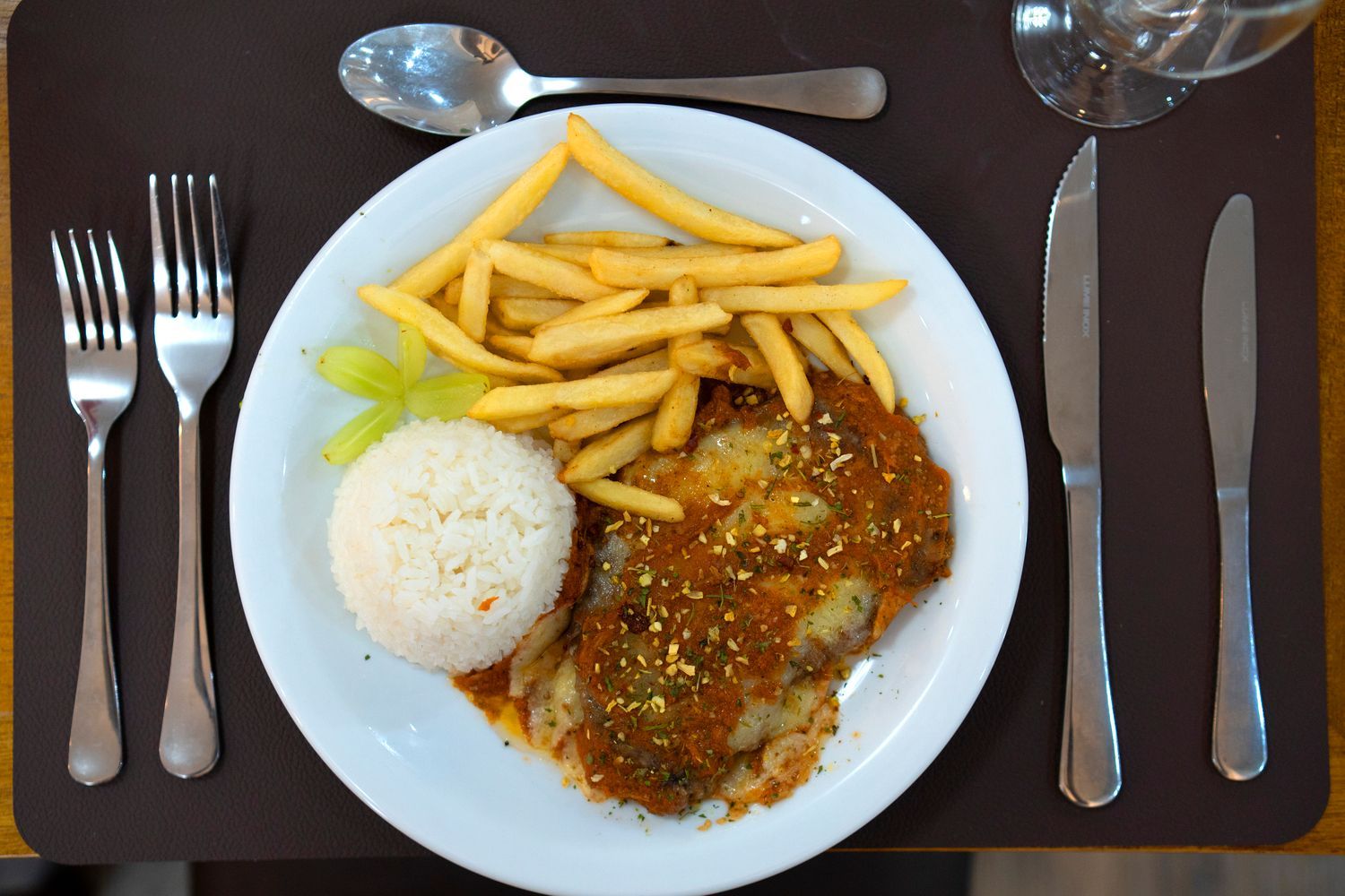 Um prato de comida com batatas fritas e arroz em uma mesa
