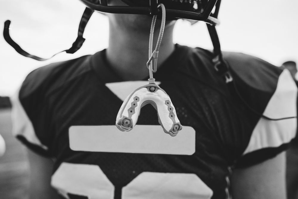 a football player with a sports mouth guard hanging from his helmet.