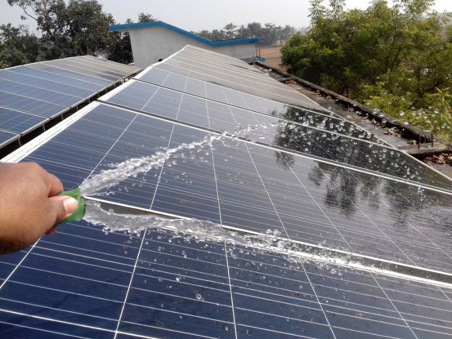 A Person is Cleaning a Solar Panel With a Spray Bottle — EDU-BABA Pressure Cleaning in Evatt, ACT