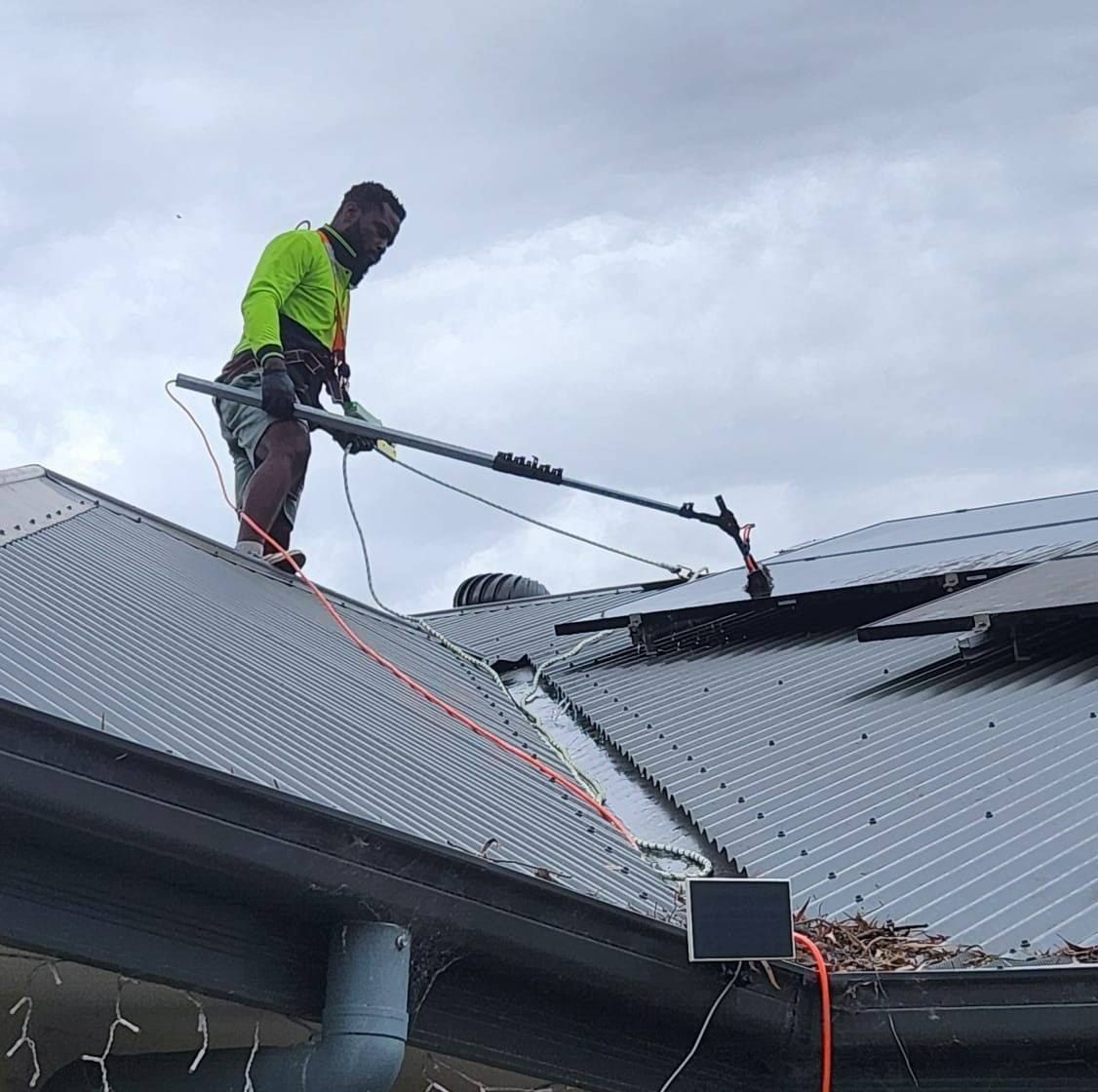 A Man is Standing on Top of a Roof — EDU-BABA Pressure Cleaning in Evatt, ACT
