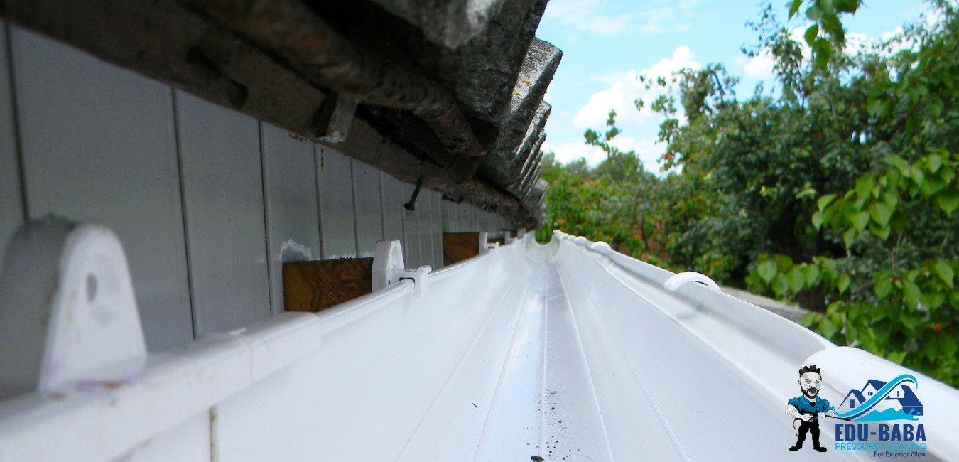 A White Gutter is Hanging From the Side of a Building — EDU-BABA Pressure Cleaning in Gungahlin, ACT