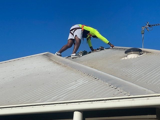 A Man is Cleaning a Tiled Roof — EDU-BABA Pressure Cleaning in Evatt, ACT