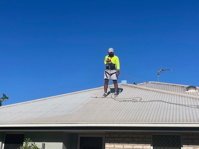 A Man is Cleaning a Tiled Roof — EDU-BABA Pressure Cleaning in Evatt, ACT