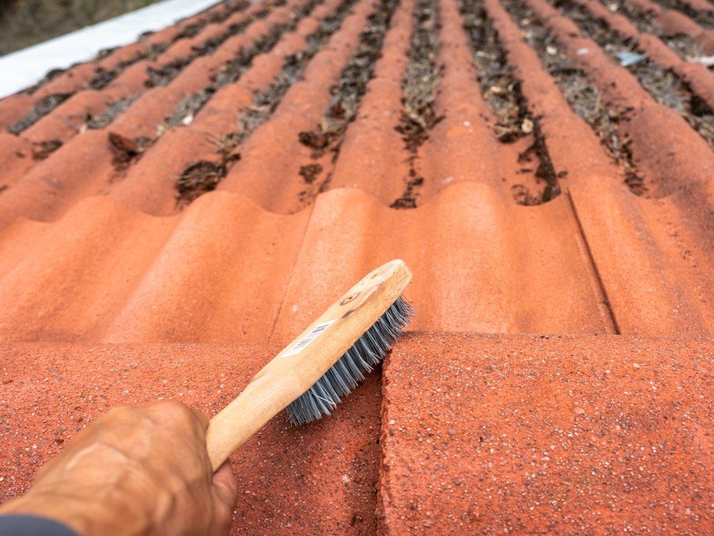 A Person is Cleaning a Roof With Wire Brush — EDU-BABA Pressure Cleaning in Belconnen, ACT