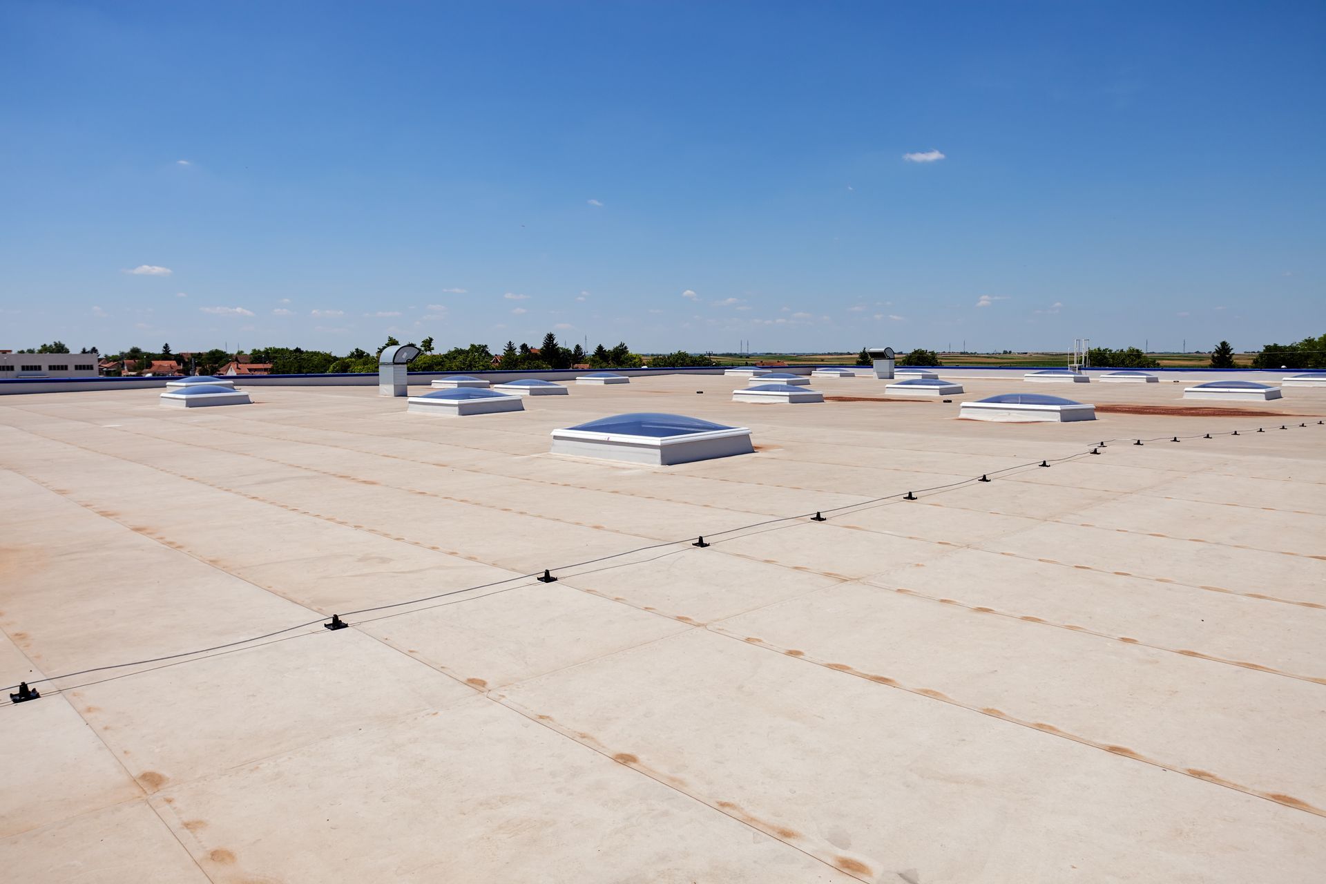 Flat commercial roof with TPO/EPDM membrane roofing and skylight domes