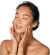 Woman applying skincare cream to her face with eyes closed.