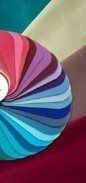 Colorful paper fan with pink, purple, blue, and teal petals on a light background
