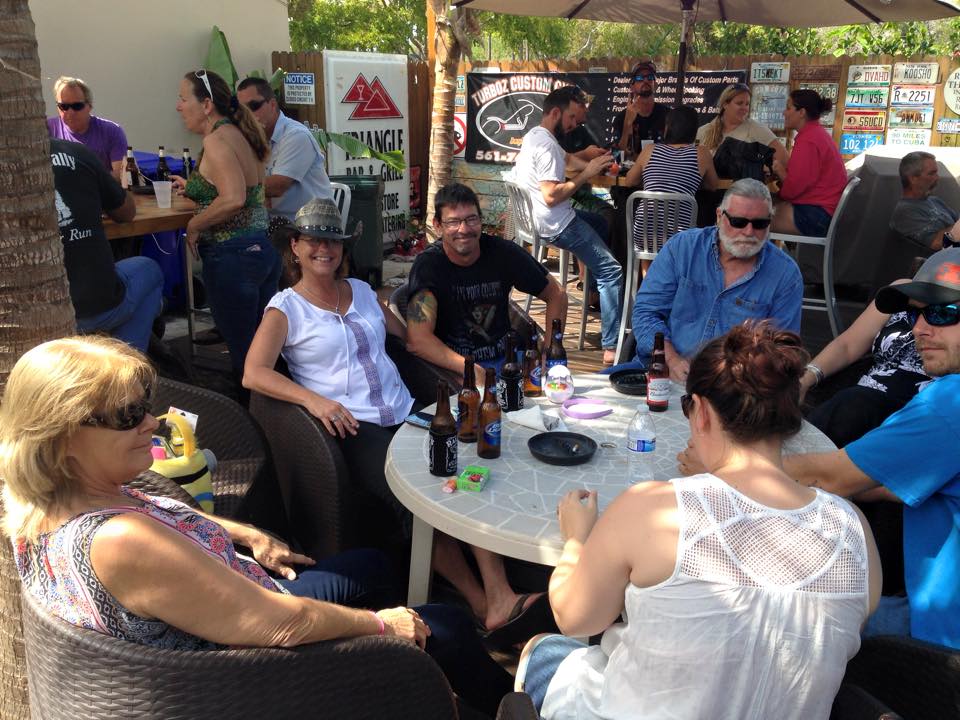A group of people are sitting around a table with bottles of beer