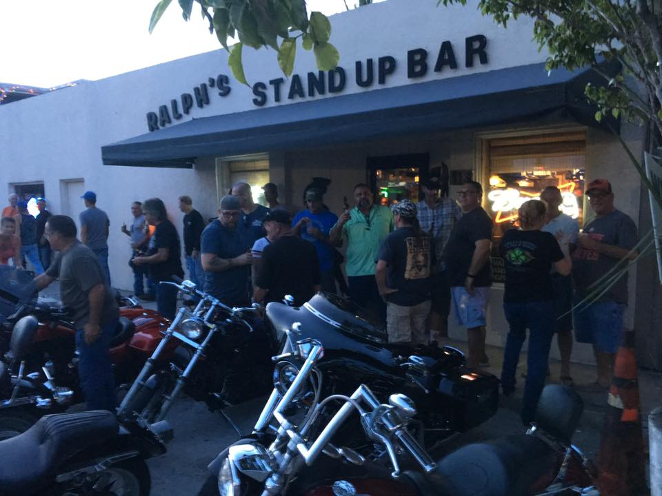 A group of people standing outside of a stand up bar