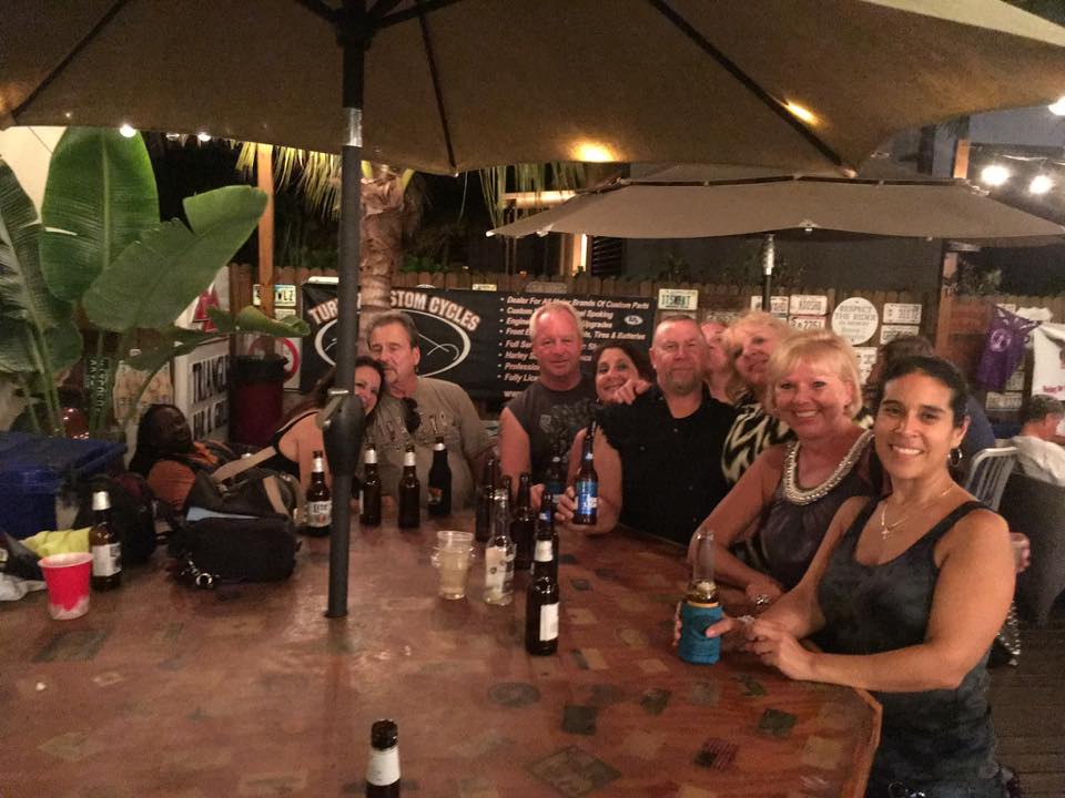 A group of people sitting at a table with bottles of beer