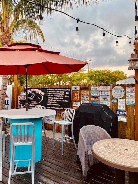 A patio with tables and chairs and a red umbrella