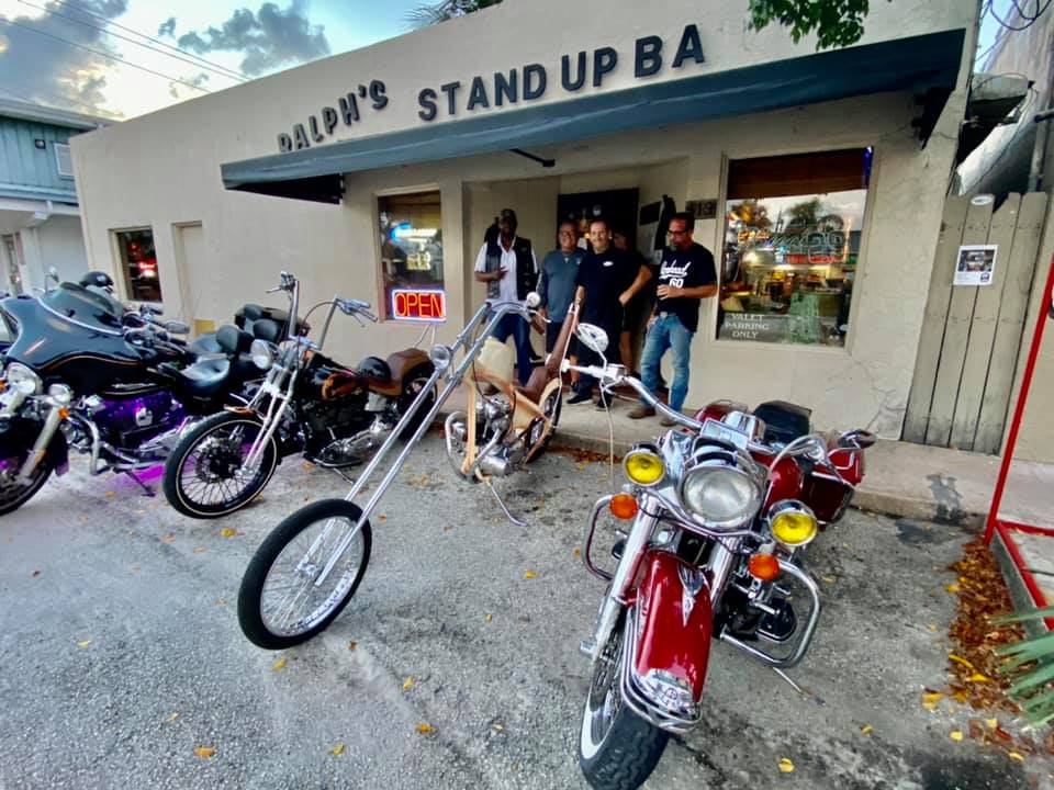 A group of motorcycles are parked in front of a stand up bar