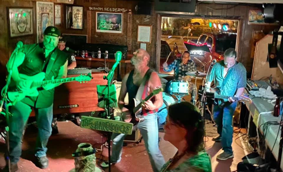 A group of people are playing guitars in a dark room.