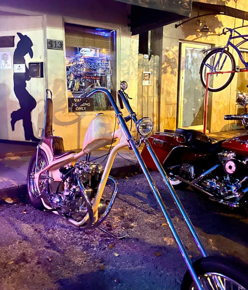 A motorcycle is parked in front of a building with the number 313 on it