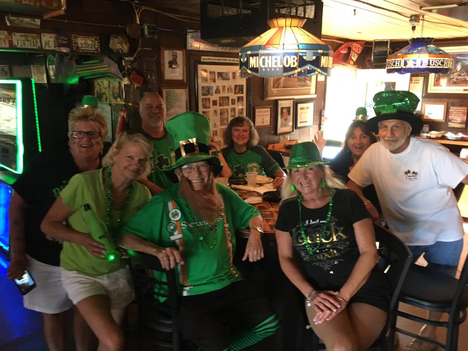 A group of people posing for a picture in a bar with a sign that says michigan on it