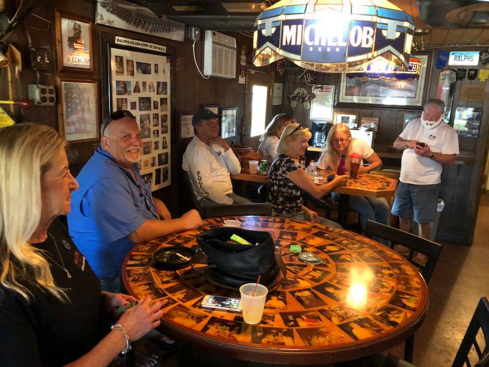 A group of people sitting around a table with a miche lob sign above them