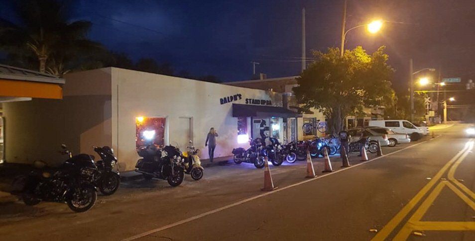 A row of motorcycles are parked in front of a building with the number 1347 on it