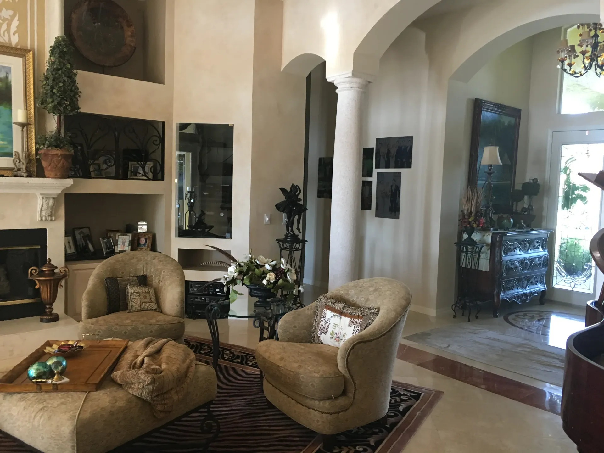 Living room with two beige armchairs, fireplace, and a doorway, decorated with art.
