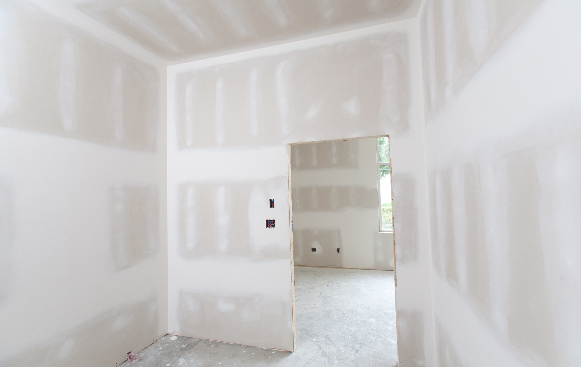 Interior of room under construction, drywall walls with doorway.