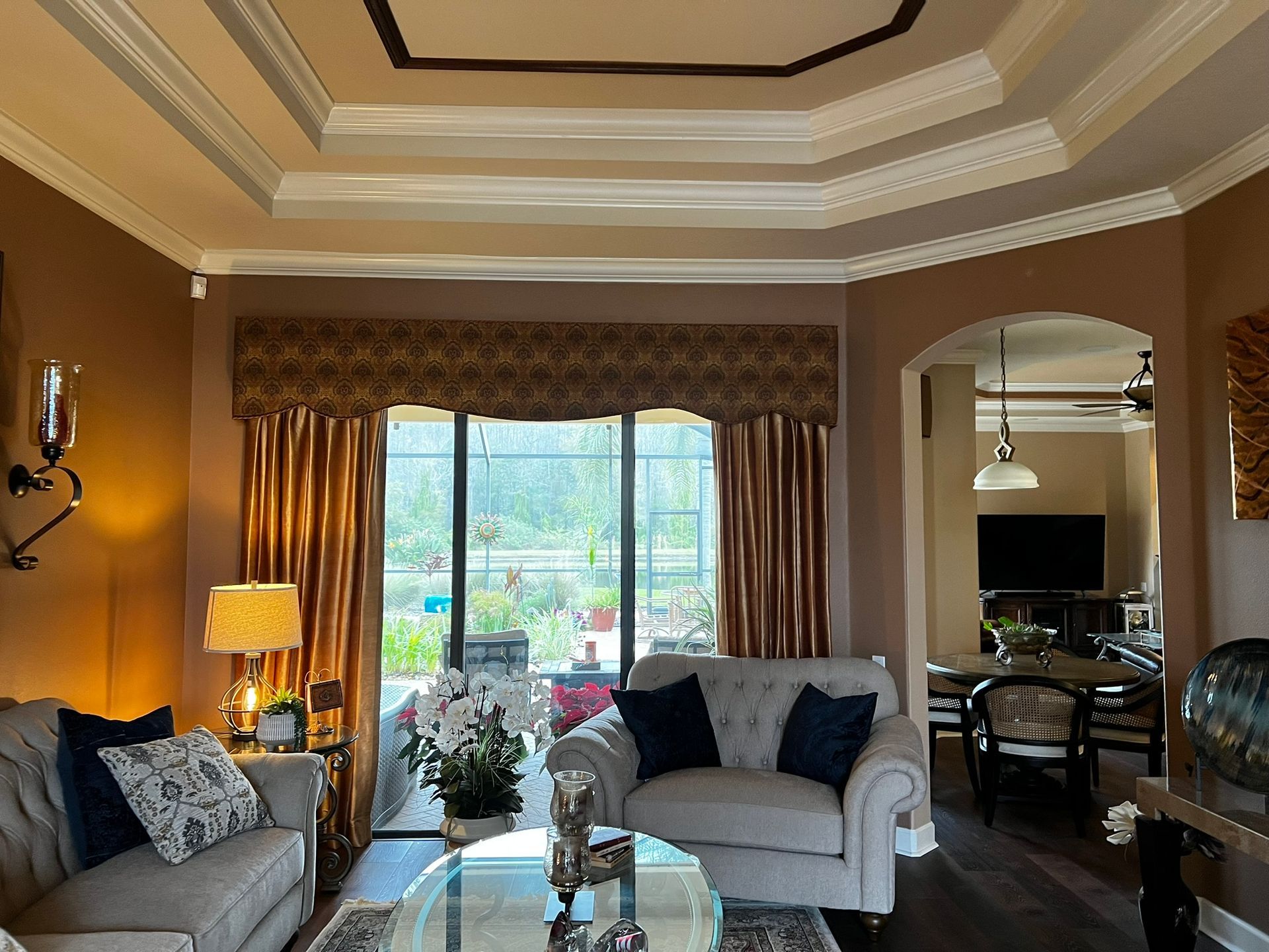 Living room with couch, window, arched doorway, and decorative ceiling.
