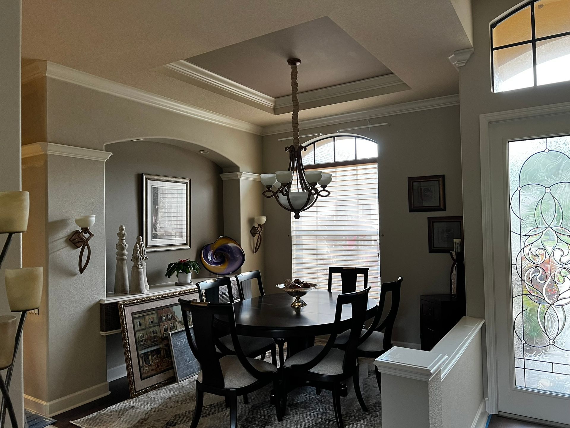 Formal dining room with dark wood table, chandelier, and arched doorway to a hallway.