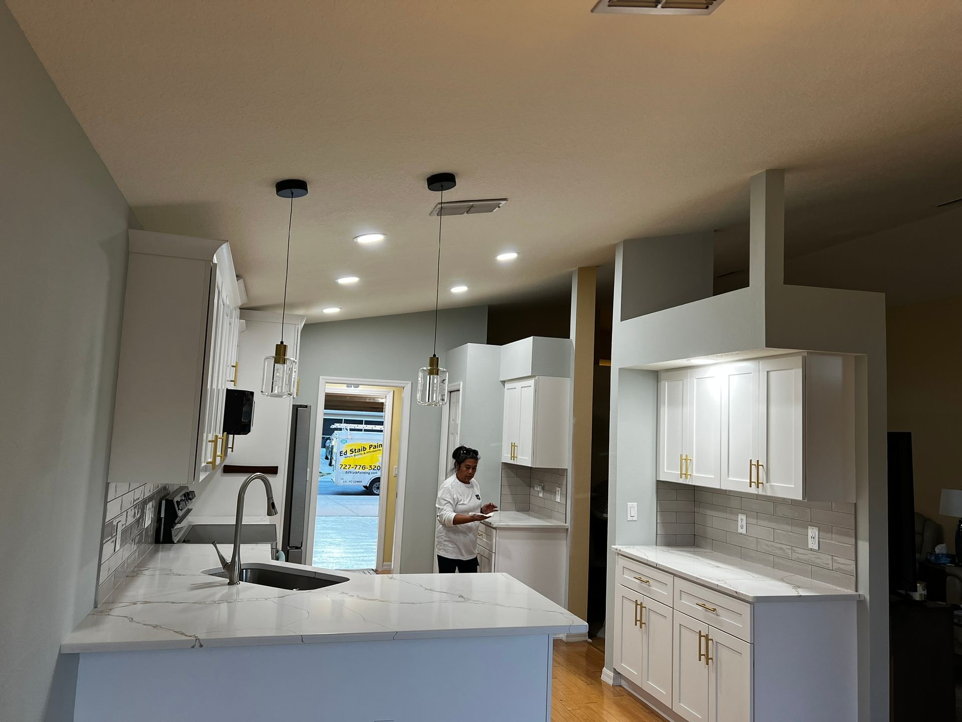 White kitchen with person standing near counter and doorway.