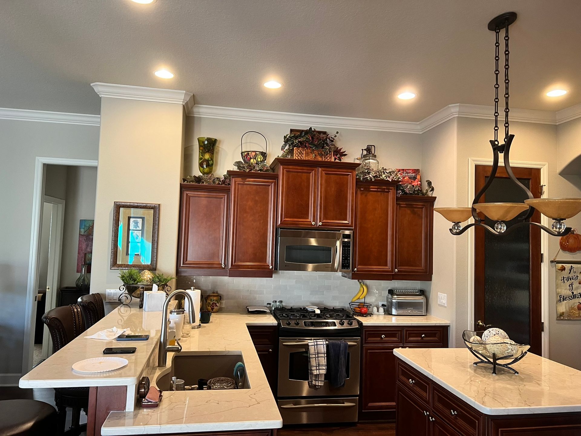 Kitchen with cherry cabinets, stainless steel appliances, and a white countertop island.