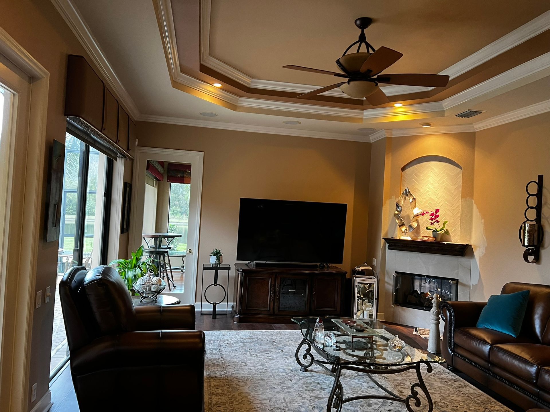 Living room with dark leather furniture, a fireplace, and a ceiling fan.