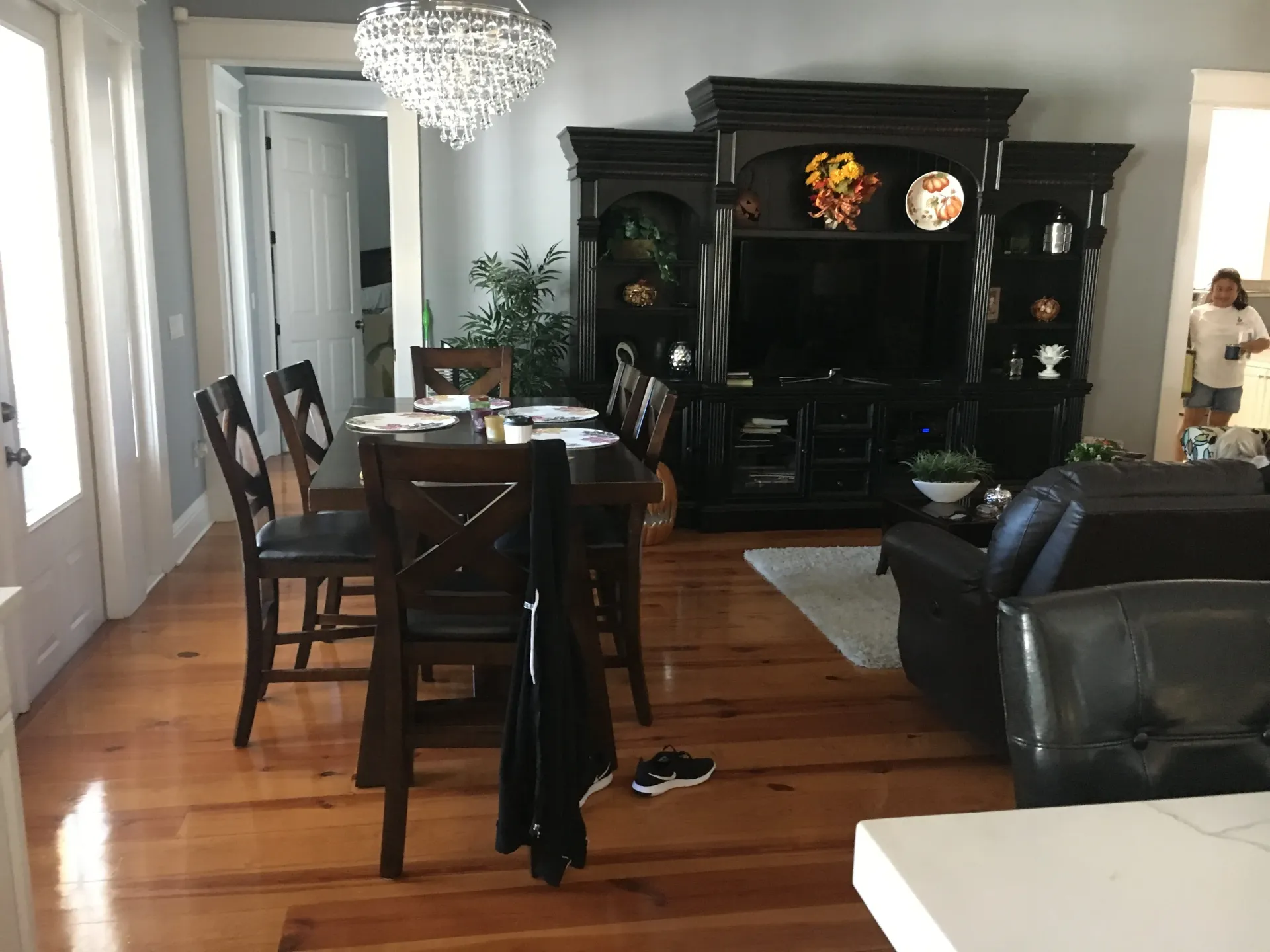 A dining room with a table set for a meal, and a large black entertainment center.