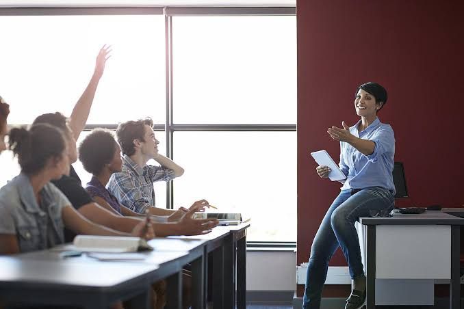 A teacher is giving a presentation to a group of students in a classroom.