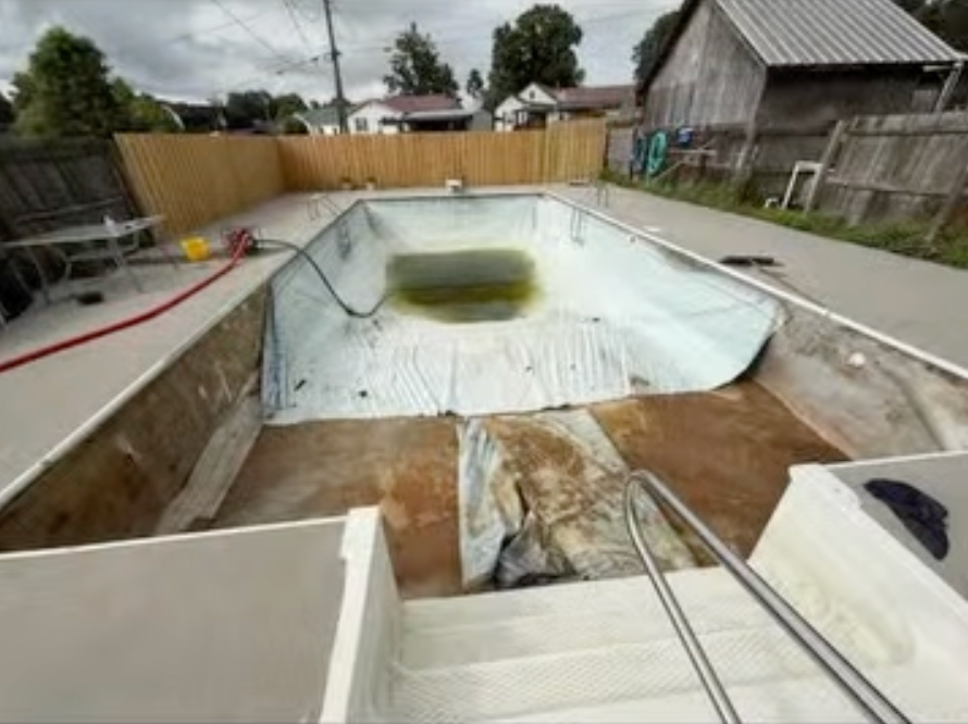 A swimming pool is being remodeled in a backyard.