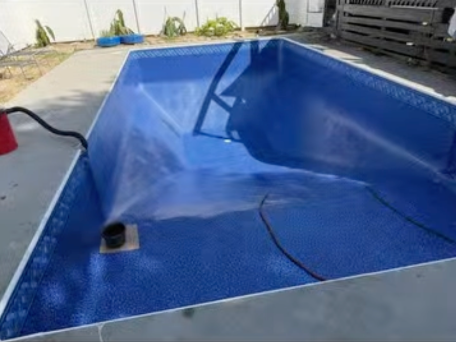 A blue swimming pool is being filled with water.