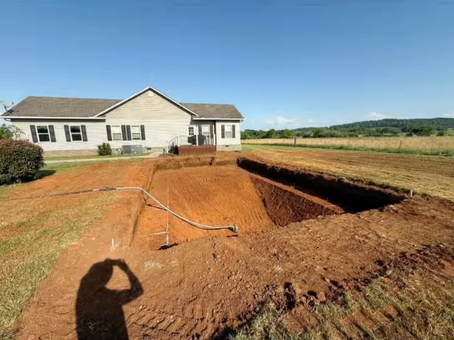 A large hole in the ground in front of a house.