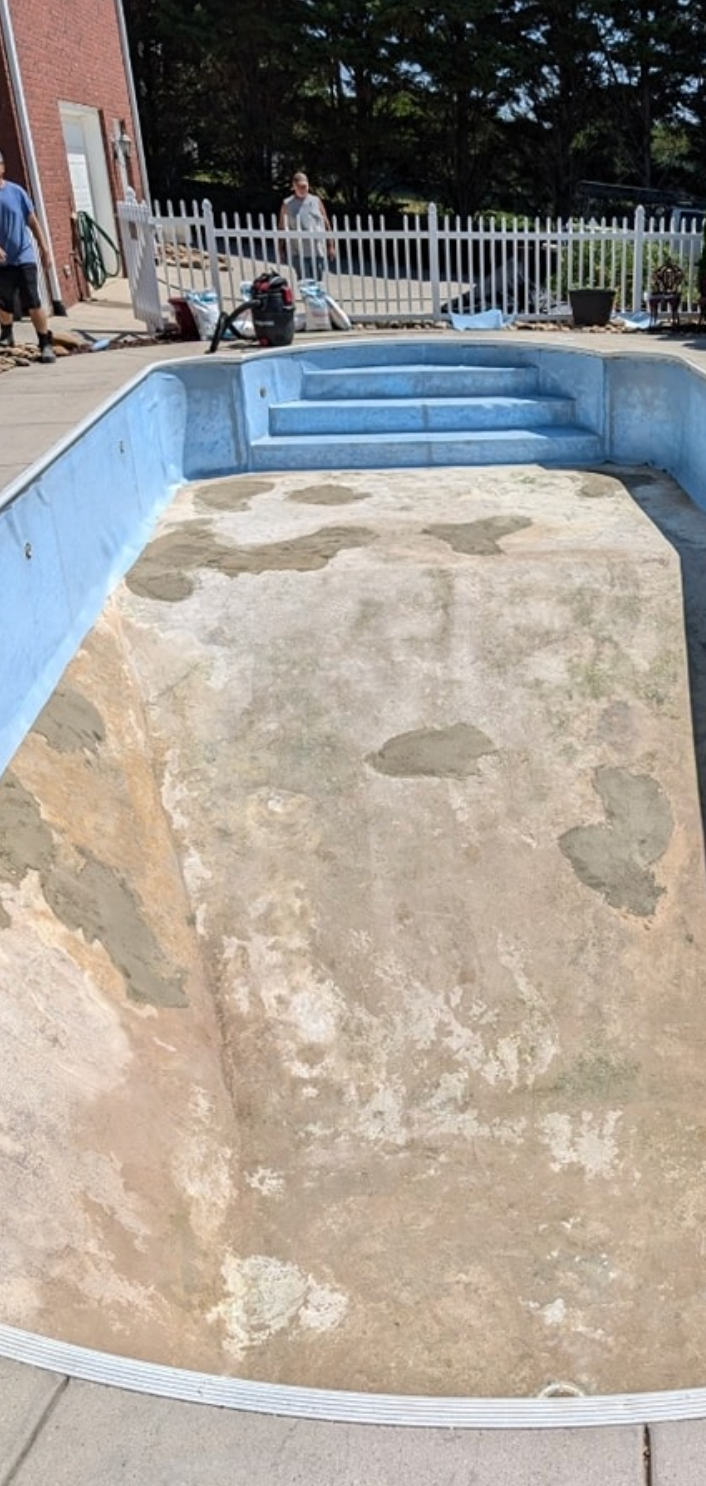 A swimming pool is being remodeled in a backyard.