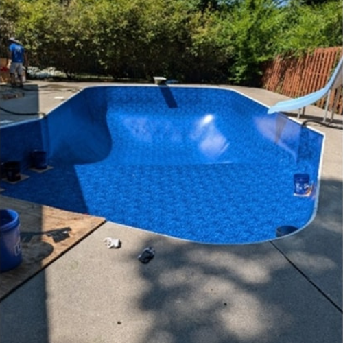 A blue swimming pool with a slide in the background.