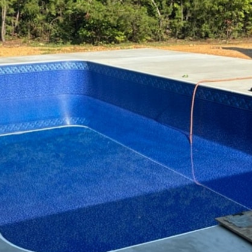 A large blue in-ground swimming pool is being built in a backyard.