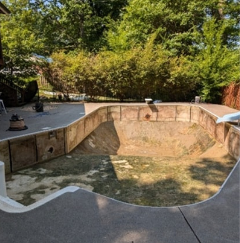 An empty swimming pool with trees in the background.