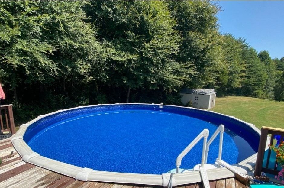 A round above-ground swimming pool with a blue cover and stairs.