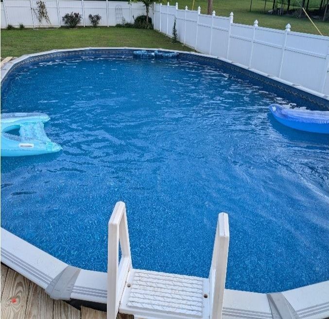 A large swimming pool with a ladder and a blue raft in it.