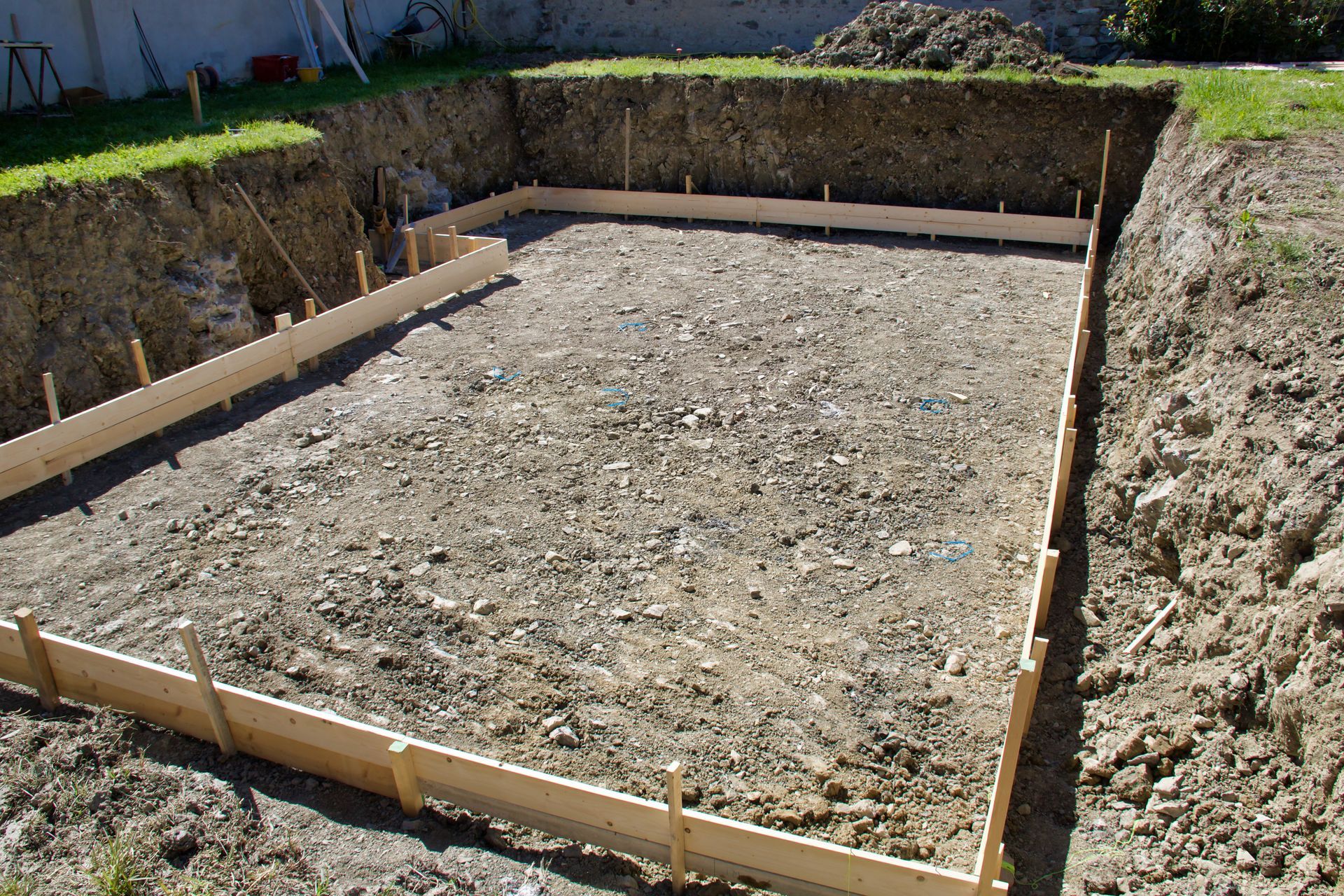 A rectangular foundation pit with wooden forms. The ground inside is covered with gravel.