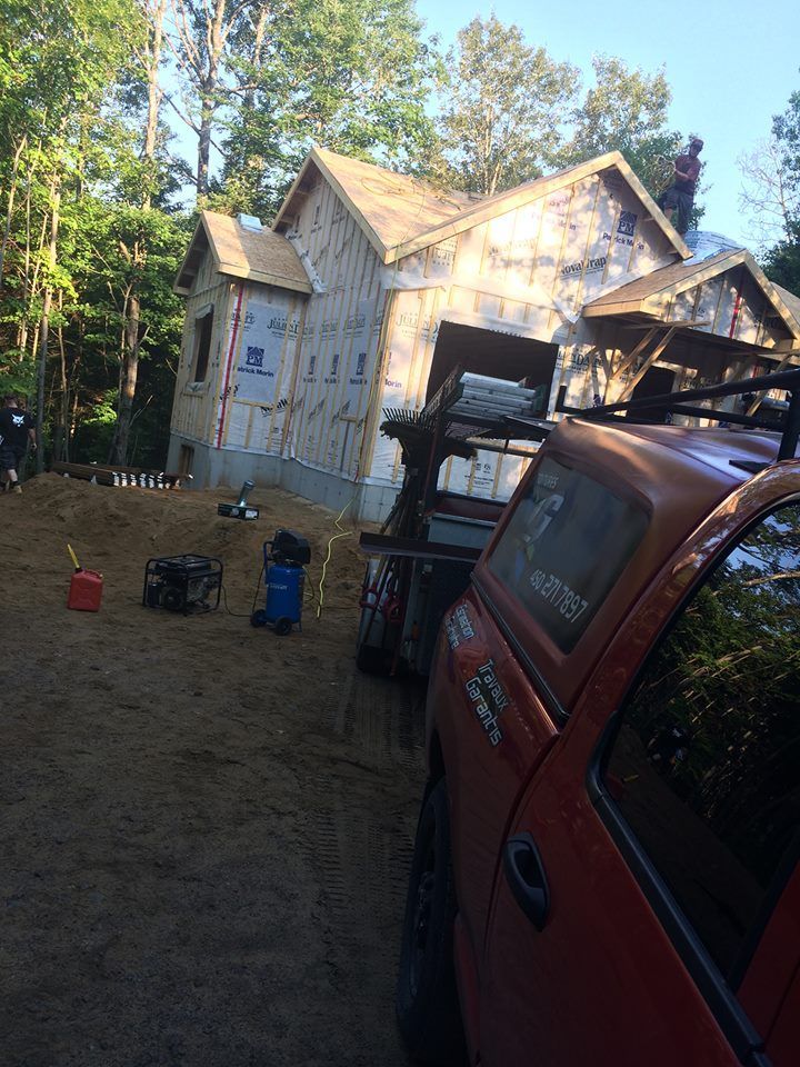 Un camion orange est garé devant une maison en construction.
