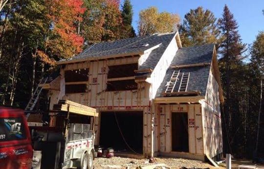 Un camion rouge est garé devant une maison en construction.