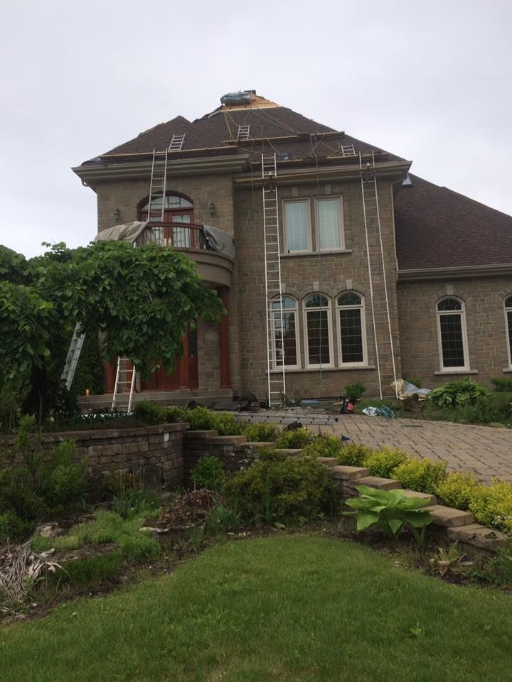 Une grande maison avec une échelle sur le toit est en cours de rénovation.