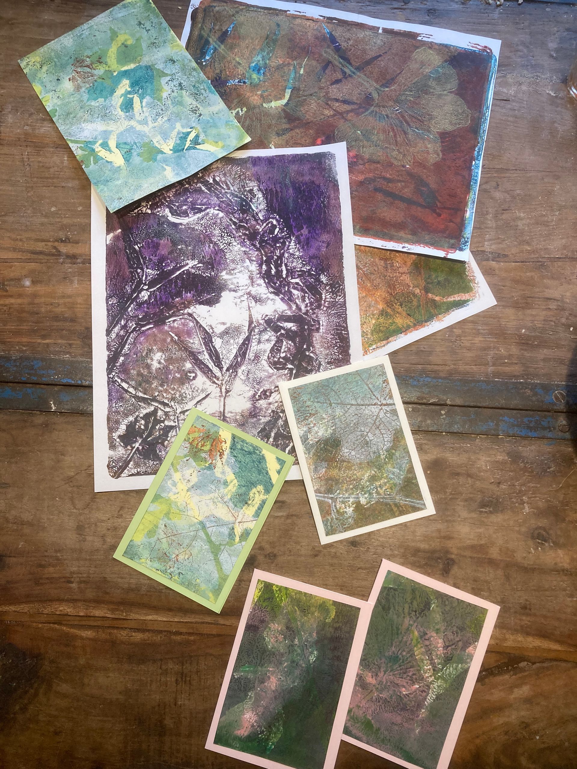 Pile of colorful abstract art prints on a wooden surface.