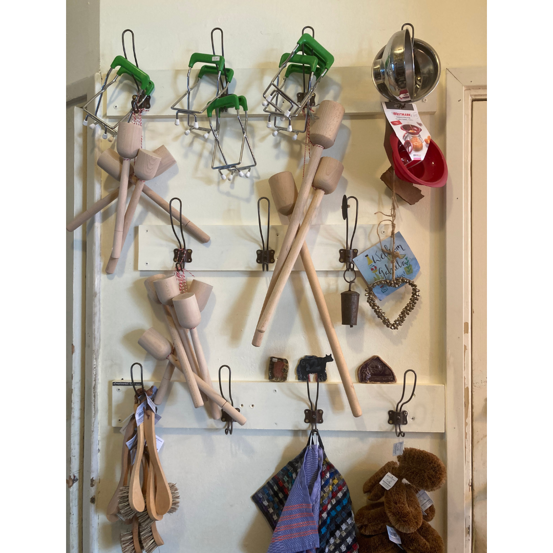 haken aan witte muur met daaraan wecktangen, wecktrechters, zuurkoolstampers, alles voor fermentatie en wecken